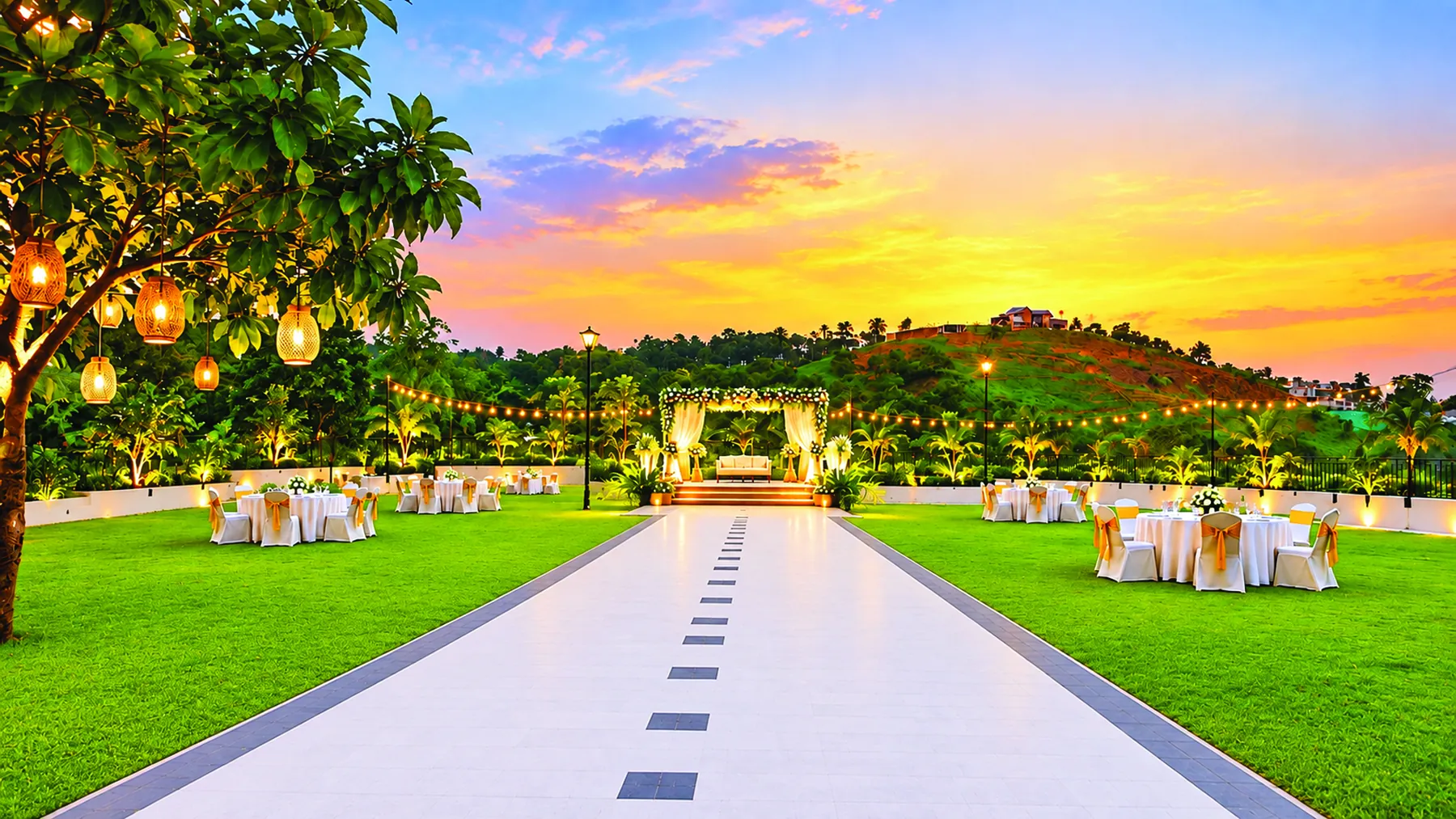 Asta, the sunset deck, laid for a reception: a floral mandap at the end of a white walkway between lawns, with lanterns in the trees