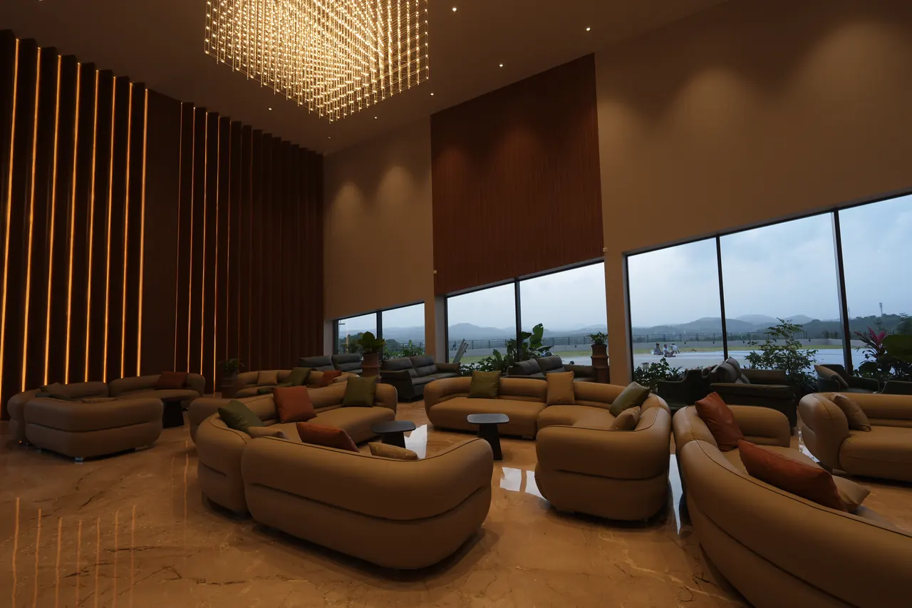 Evening lounge with panoramic windows framing the Kerala hills at twilight