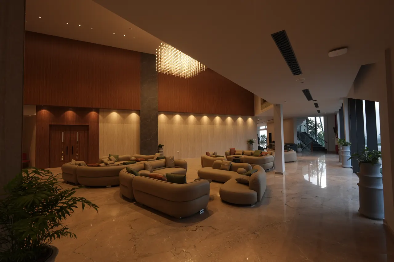 Lobby at dusk beneath a crystal chandelier with curved sofas on polished marble