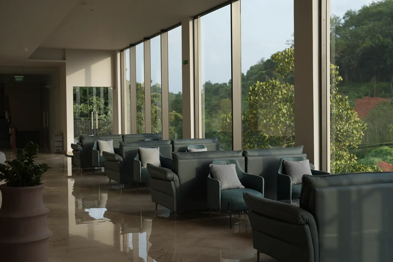 Lounge seating along the glass curtain wall with views over the wooded valley outside Manjeri