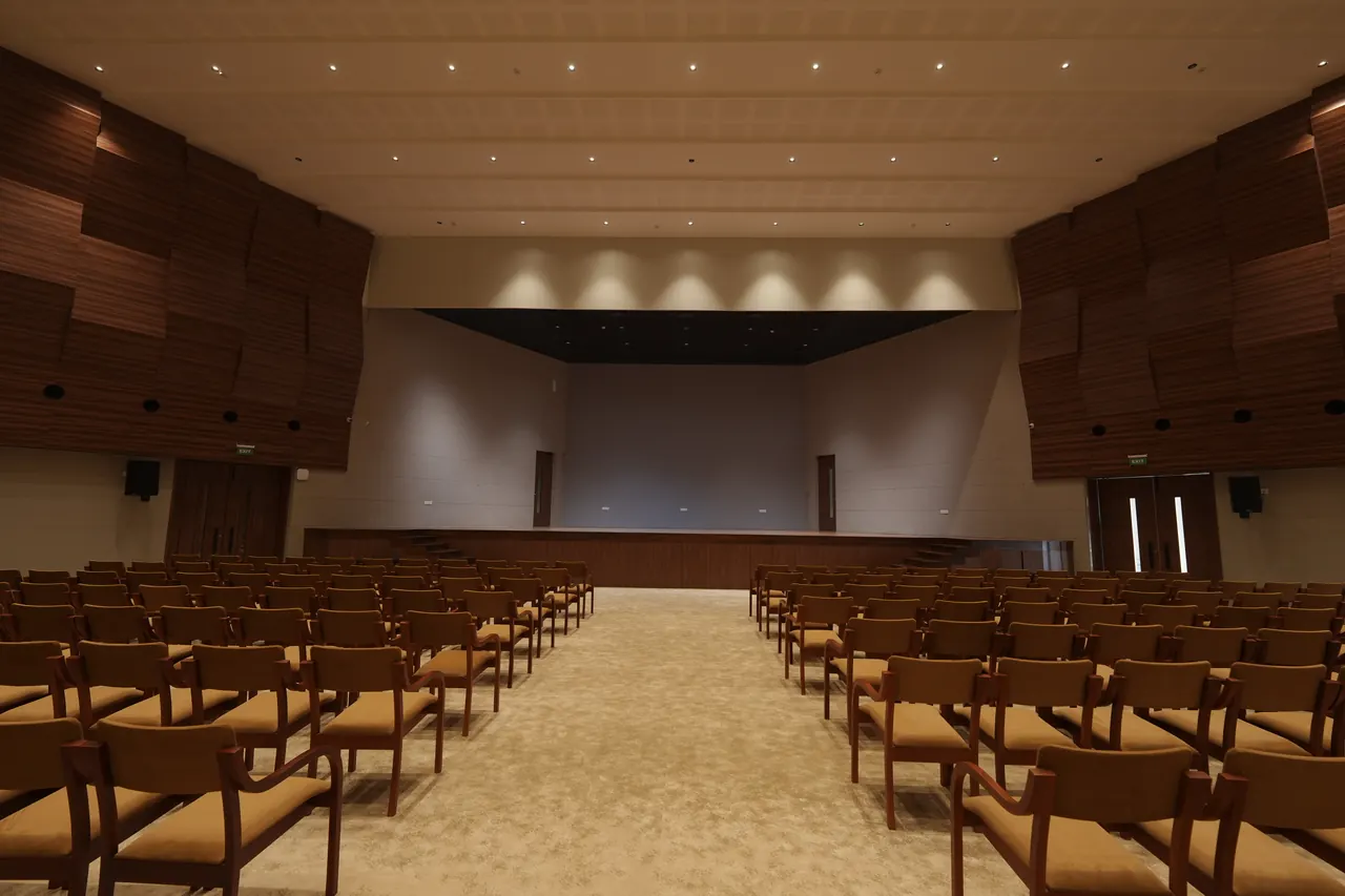 Stage and centre aisle of the auditorium framed by timber acoustic panelling